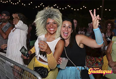 Dos chicas sonriendo, con bebida en mano en El Gran Guateque