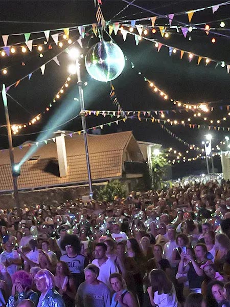 P�blico disfrazado cantando y bailando bajo la bola de espejos en El Gran Guateque