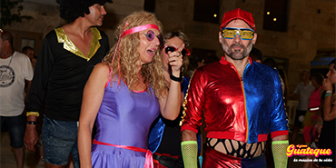 Personas bailando con trajes retro y futuristas de los 80s en El Gran Guateque
