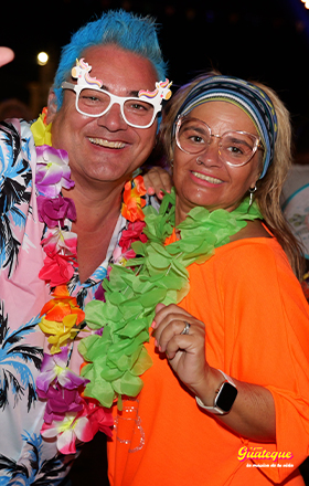 Pareja veraniega de finales de los 80 y principios de los 90, vestida con guirnaldas hawaianas, colores llamativos y sonrientes en El Gran Guateque